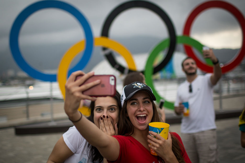 Meninas tiram foto em frente aos arcos olímpicos