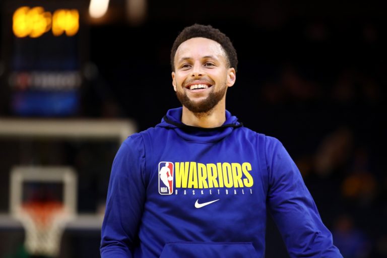 Stephen Curry sorri em quadra durante partida de basquete pelo Golden State Warriors