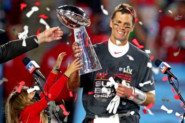 Tom Brady sorrindo e segurando um prêmio