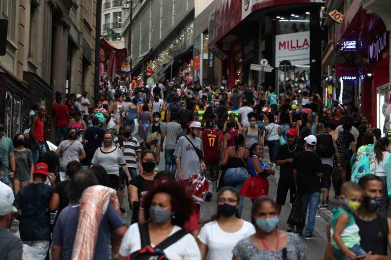Imagem mostra pessoas andando em rua comercial de São Paulo