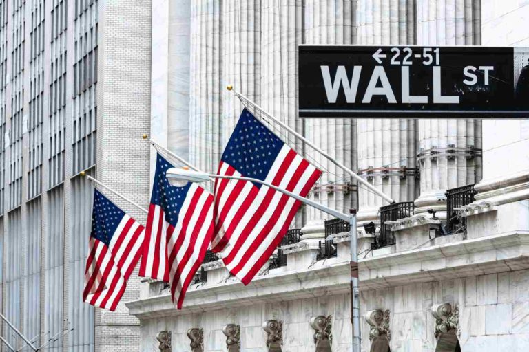 Placa de rua de Wall Street com bandeiras dos Estados Unidos hasteadas ao fundo