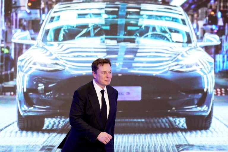 Foto de Elon Musk em frente a um painel da Tesla