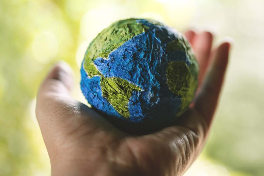 Globo terrestre sendo segurado por uma mão aberta, em oferecimento