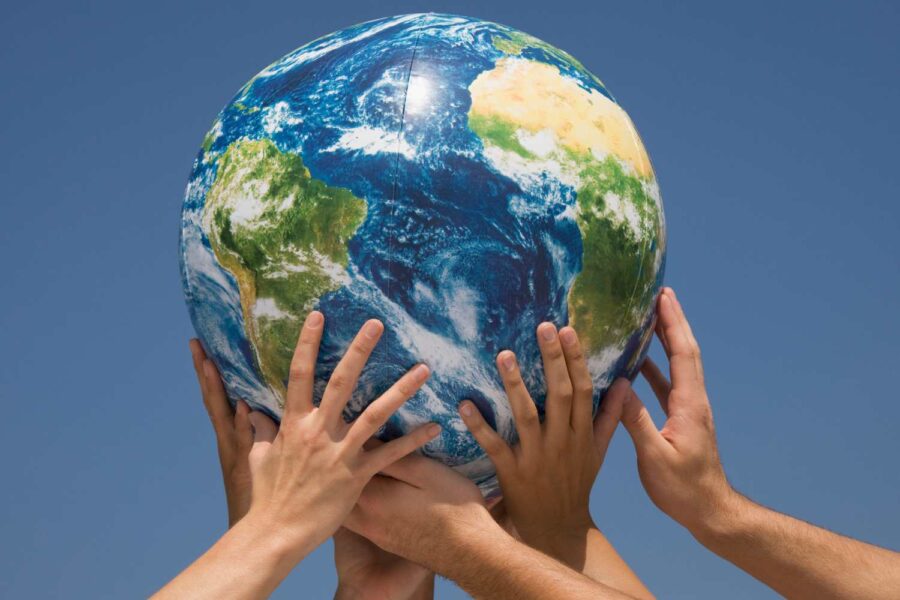 Globo terrestre contra um fundo azul, segurado por várias mãos