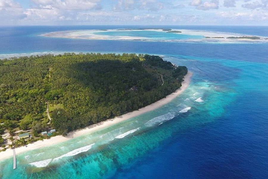 Ilha com vegetação nativa, de mar muito transparente e em várias tonalidades de azul