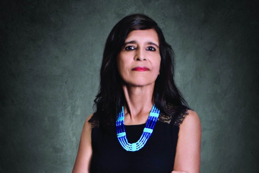 Mulher branca com blusa preta e colar azul