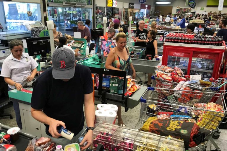 Pessoas pagam produtos em caixas de supermercado