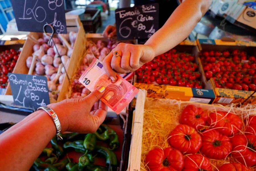 Imagem mostra uma mulher recebendo 10 euros em uma feira