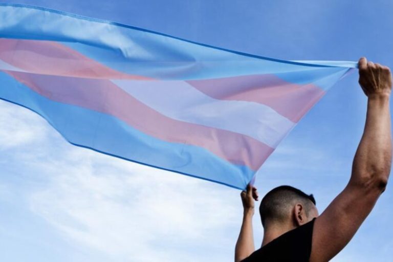 homem segura bandeira trans em apoio à transição de gênero