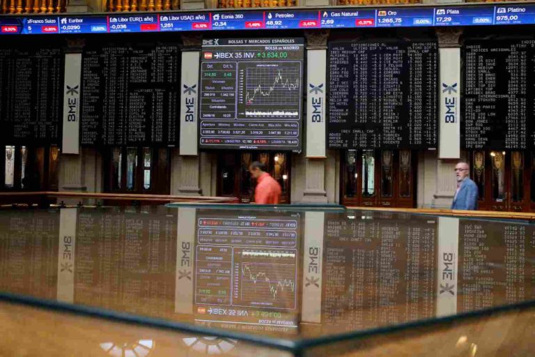 Homens passam em sala de tela com índices de ações da bolsa na Europa