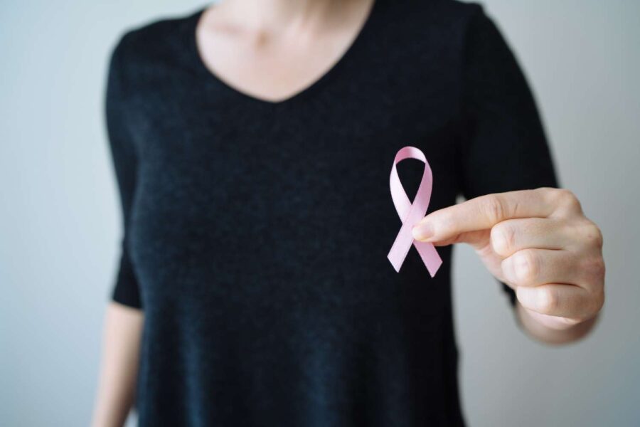 Mulher segurando laço rosa na mão