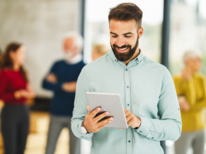 Homem branco segurando um tablet na mão direita