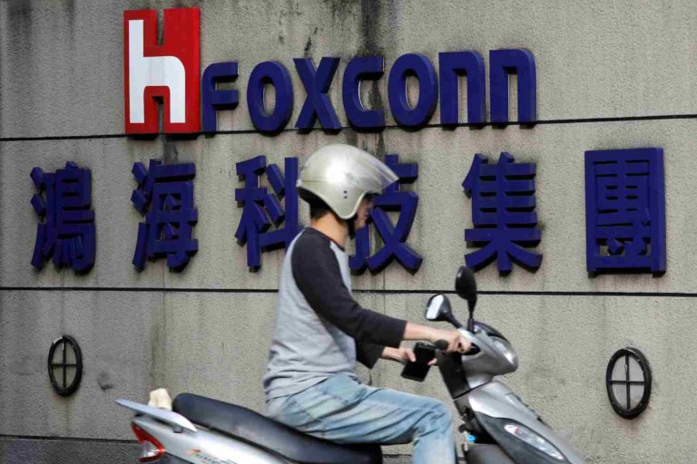 Pessoa de moto na frente do logo da Foxconn