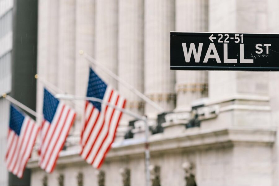 Placa de rua de Wall Street com bandeiras dos Estados Unidos hasteadas ao fundo