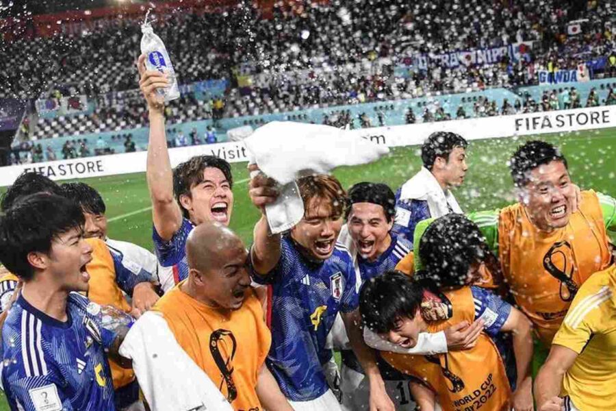 Jogadores de futebol comemoram e jogam água para o alto em um campo de futebol