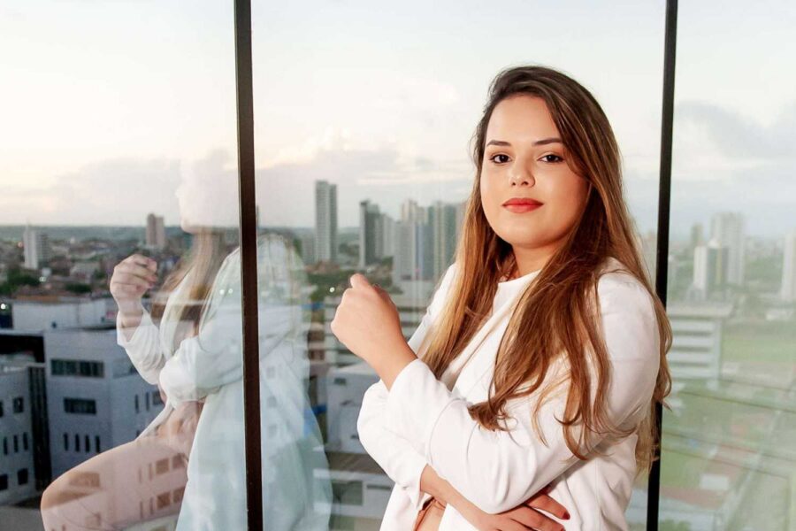 Mulher olhando séria para câmera na frente de janela