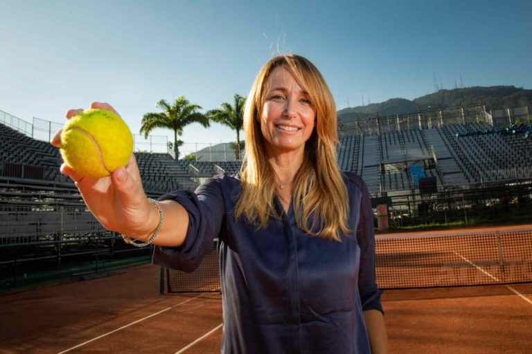 Marcia Casz segurando uma bolinha de tênis e sorrindo para a câmera
