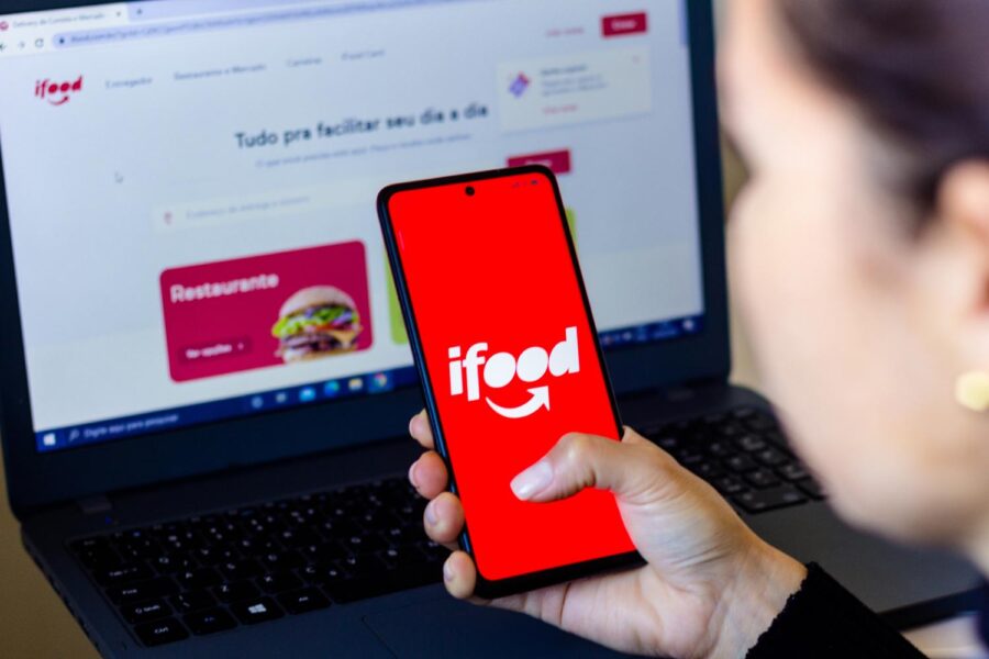 Pessoa mexendo em celular com o logotipo do iFood