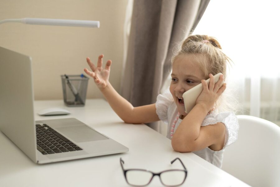 Menina brincando com computador e celular