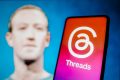 Mark Zuckerberg, CEO da Meta, ao lado de um celular com o logo da rede social "Threads"