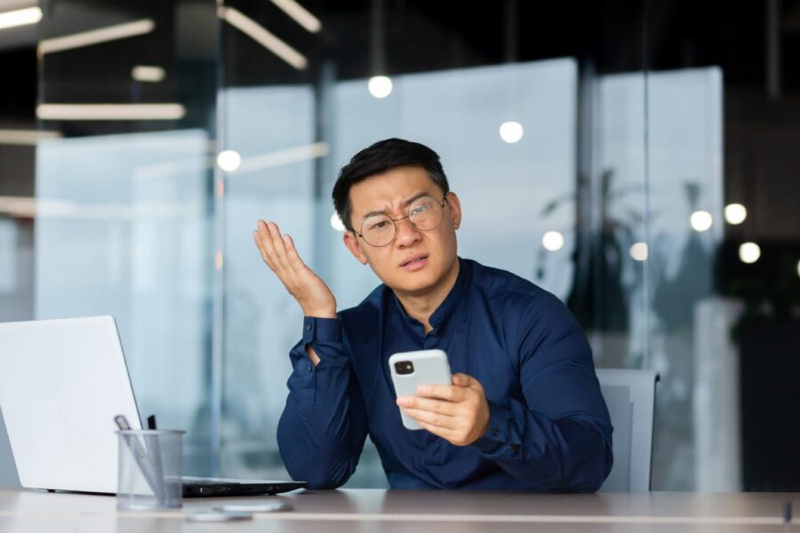 Homem segurando celular com expressão de dúvida