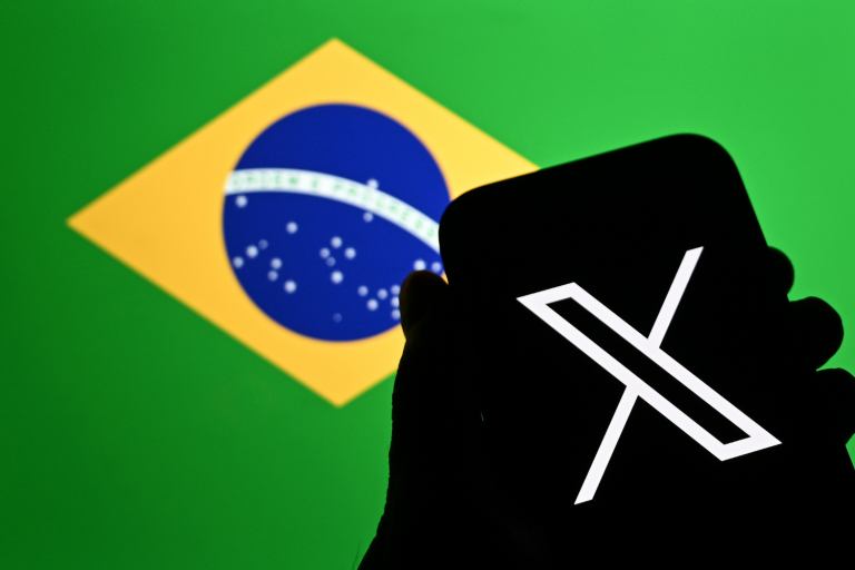 Celular com logo do X (Twitter) em frente a uma ilustração da bandeira do Brasil