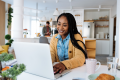 Foto de uma mulher negra sorrindo enquanto realiza um curso online