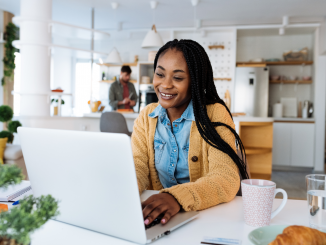 Foto de uma mulher negra sorrindo enquanto realiza um curso online