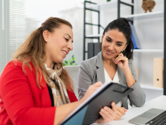 Duas mulheres conversando enquanto uma delas mostra uma tarefa em um tablet