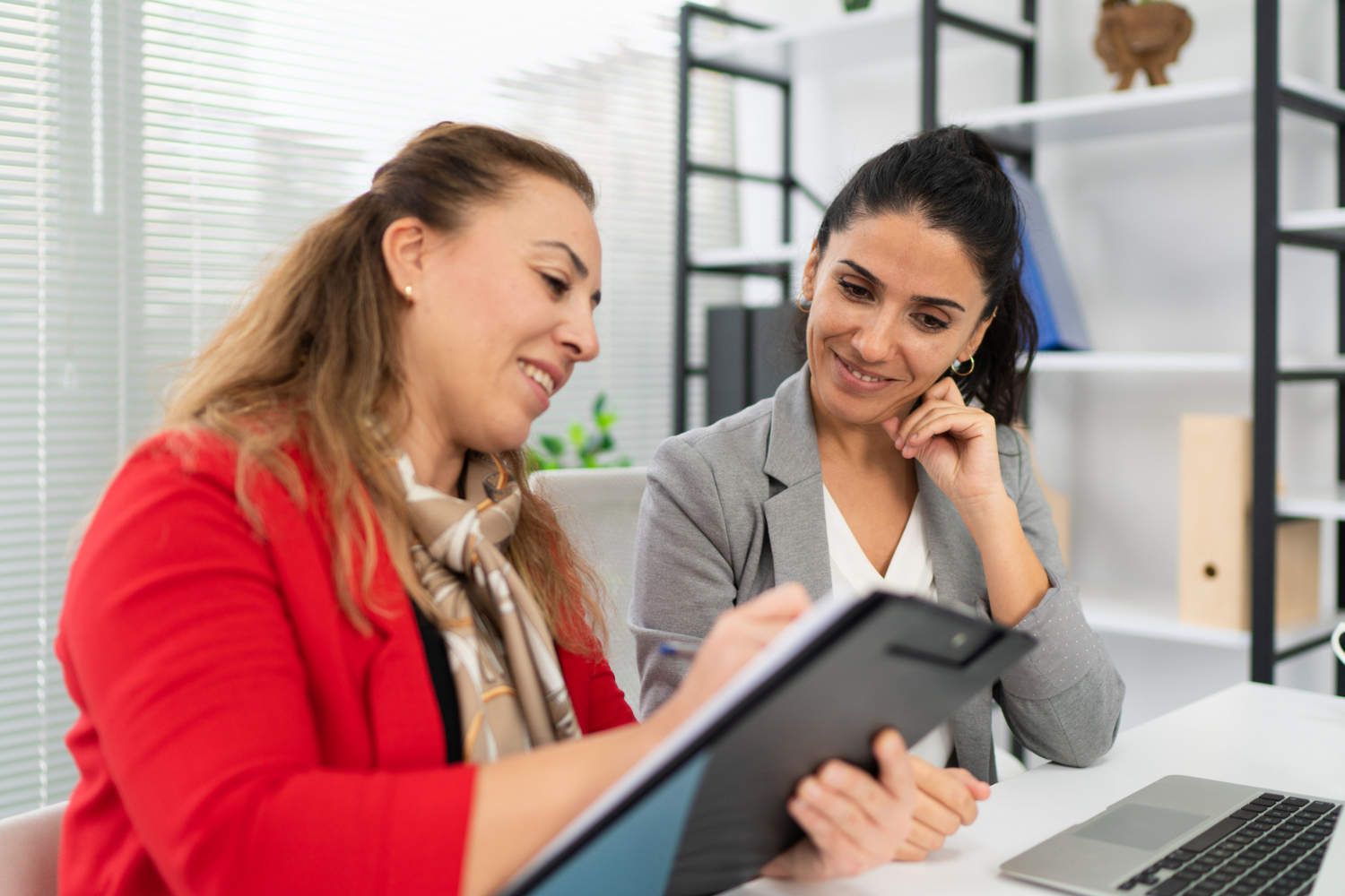 Duas mulheres conversando enquanto uma delas mostra uma tarefa em um tablet