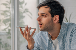 Homem utilizando um celular para fazer uma gravação de voz