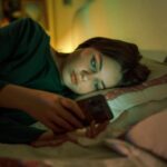 jovem mexendo no celular deitada na cama