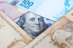 A moeda brasileira cobre uma nota de 100 dólares