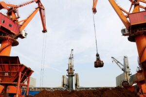 Guindastes descarregam minério de ferro importado de um navio de carga em um porto em Lianyungang, província de Jiangsu, China