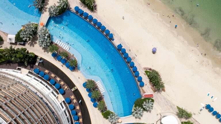 Praia com equipe e hóspedes fazendo a limpeza da areia durante a manhã no resort que tem certificado de baixo carbono