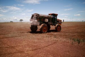 Trator espalhando fertilizante em um campo de soja, perto de Brasília, no Brasil